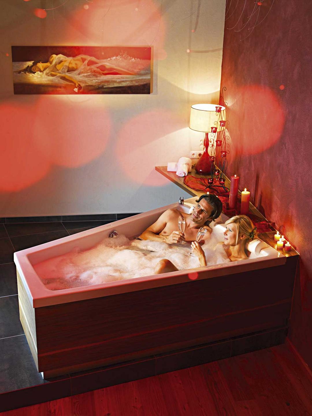 Paar entspannt im Hotel Goies bei einem Glas Champagner und bei Kerzenschein in der Badewanne